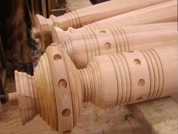 Top of wood column with large elliptical shaped finial that has both circular cutouts and ring detail.